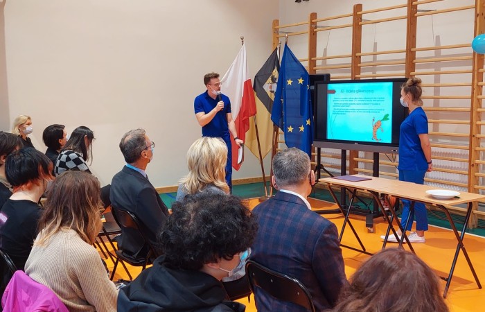 osoby oglądające prezentacje na sali gimnastycznej w TV