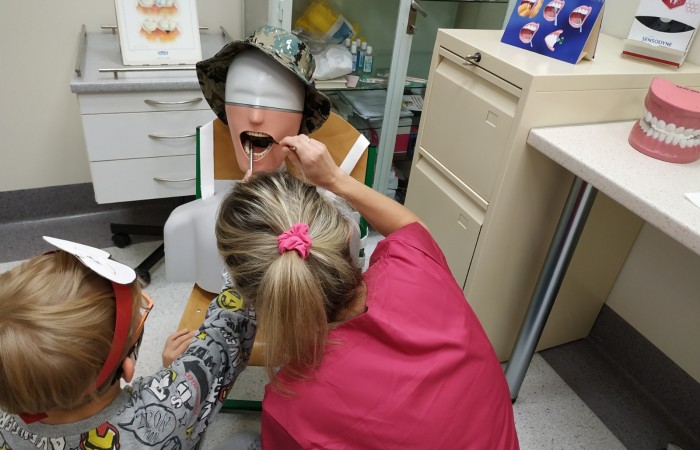 Dzieci na hali sportowej uczą się dbania o zęby i jamę ustną.