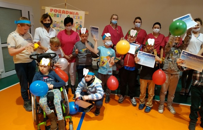 Dzieci na hali sportowej uczą się dbania o zęby i jamę ustną.