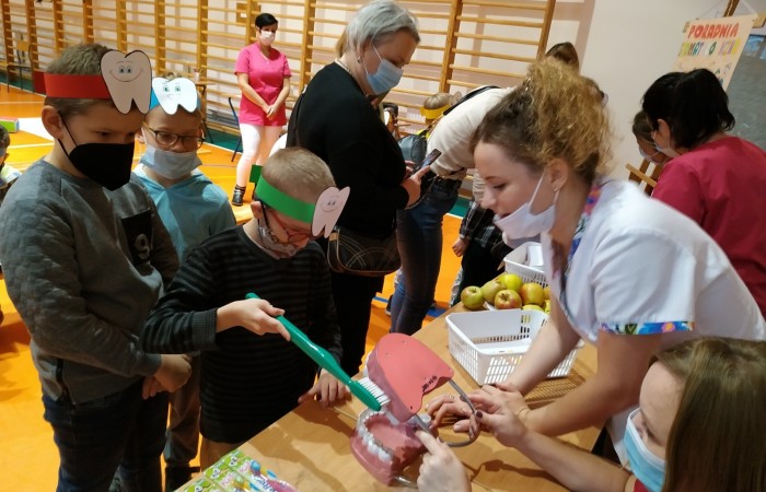 Dzieci na hali sportowej uczą się dbania o zęby i jamę ustną.