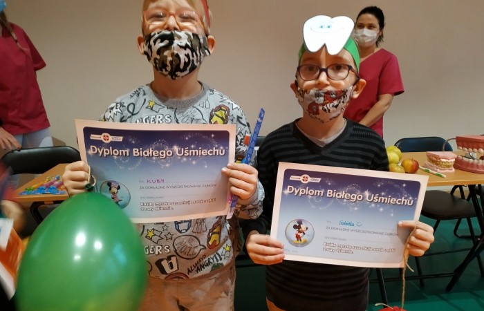 Dzieci na hali sportowej uczą się dbania o zęby i jamę ustną.