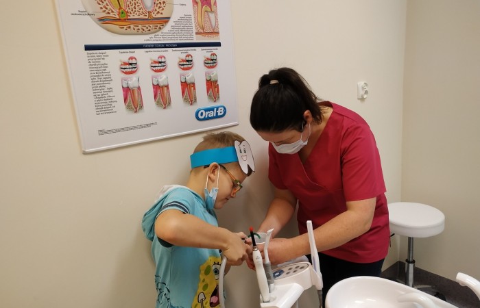 Dzieci na hali sportowej uczą się dbania o zęby i jamę ustną.