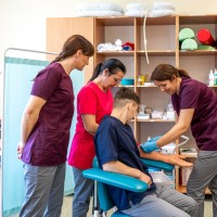 Nauka pobierania krwi z manekina widok uczniów przy krześle