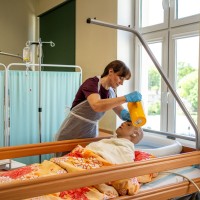 Uczeń myjący manekinowi pacjentowi włosy w łóżku