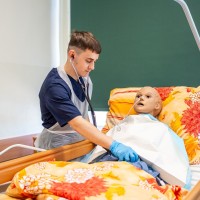 Uczniowie układający manekina pacjenta w łóżku.