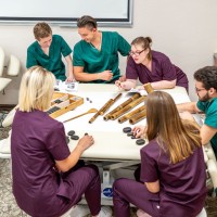 Uczniowie siedzący przy stole poznający narzędzia do masażu