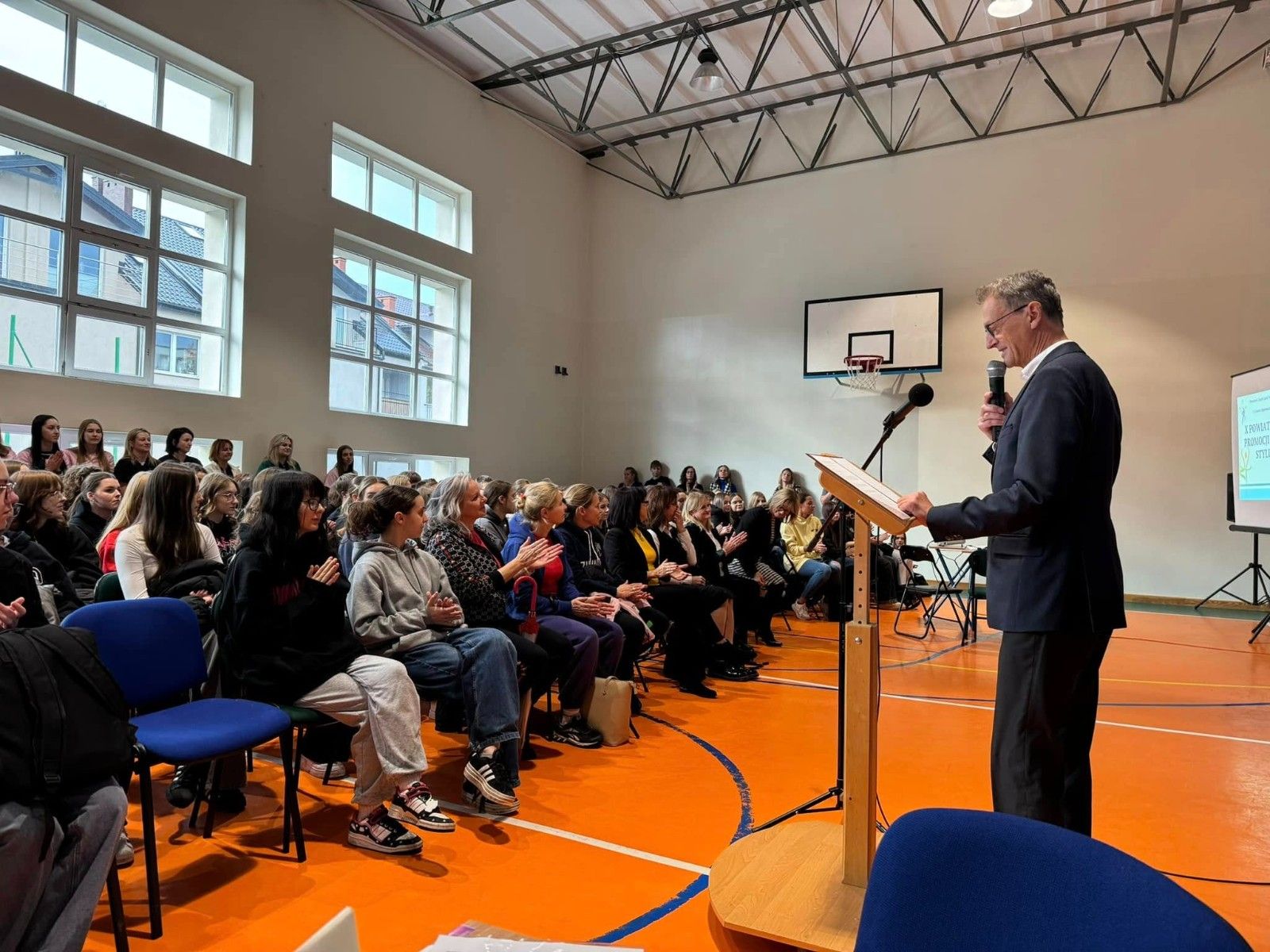 Widok na gości słuchających przemówienie  Dyrektora Szkoły.