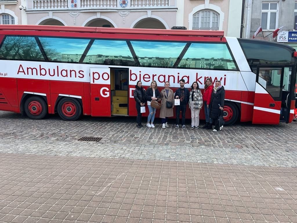 Wspólne zdjęcie grupowe na tle autobusu.