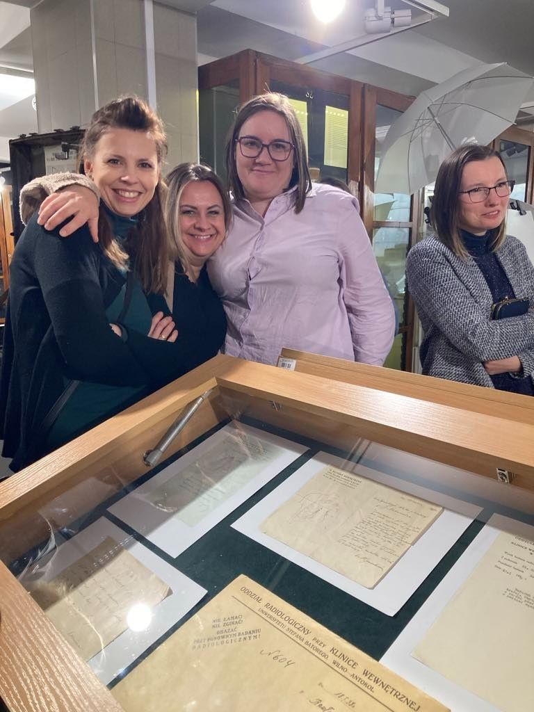 Wspólne zdjęcie uczennic przy gablocie z dokumentami.