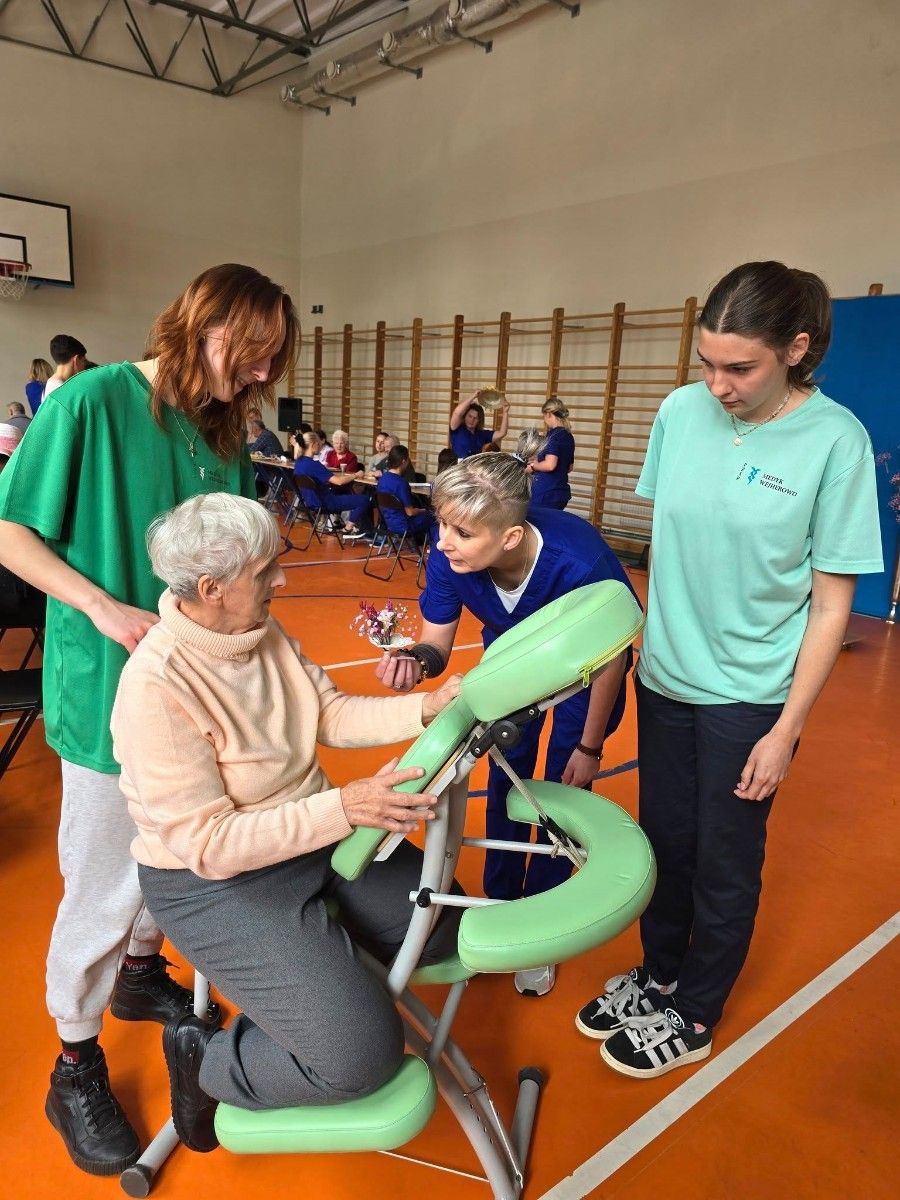 Uczennice wręczające prezent seniorce.