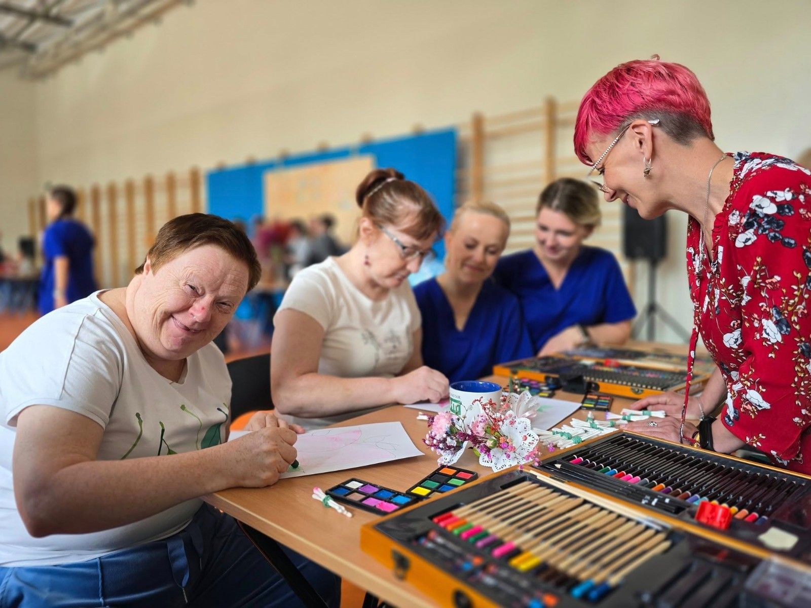 Seniorzy wykonujący prace plastyczne przy stole.