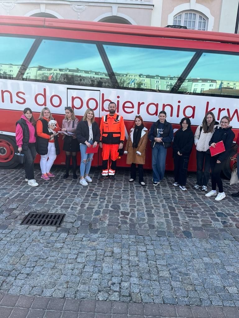 Wspólne zdjęcie z ratownikiem w tle z autobusem do zbiórki krwi.