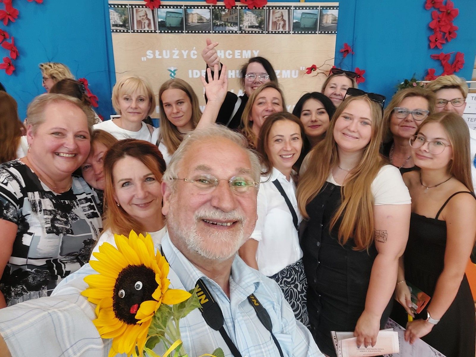 Zdjęcie uczniów z nauczycielem trzymający kwiatek.