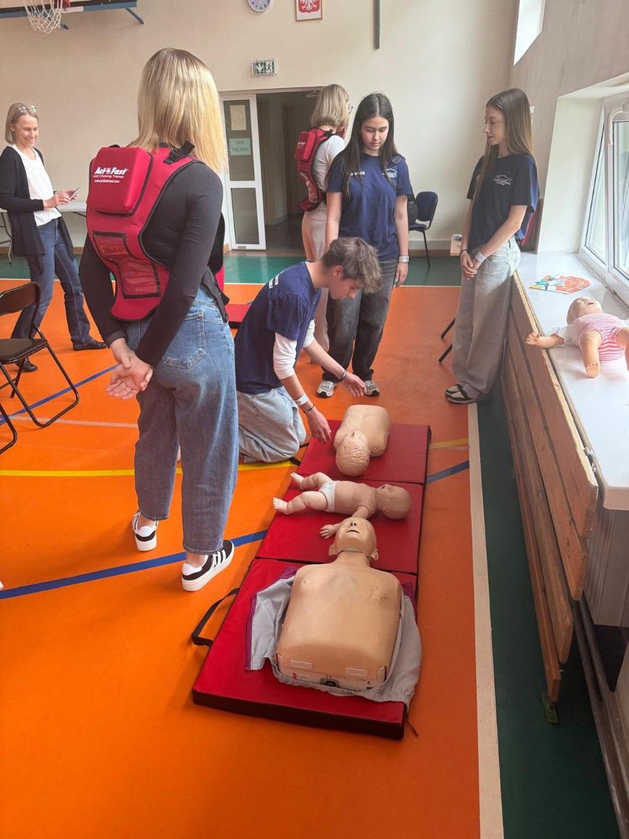 Zdjęcie na uczestników wykonujących reanimację na manekinie.