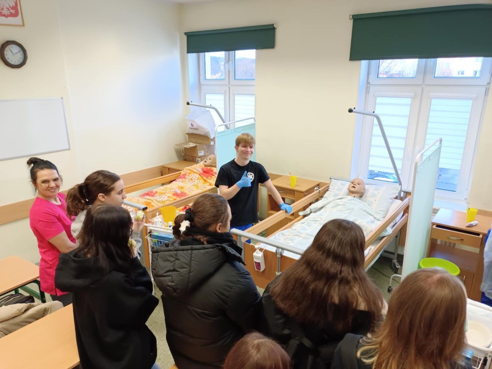 Uczniowie prezentujący pracę z chorym na manekinie w łóżku.