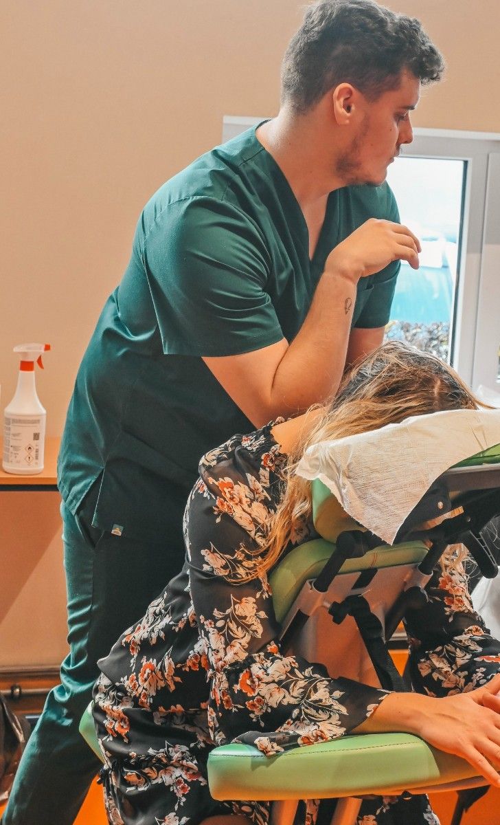 Widok na ucznia wykonujący masaż na  gościu na specjalnym stole.