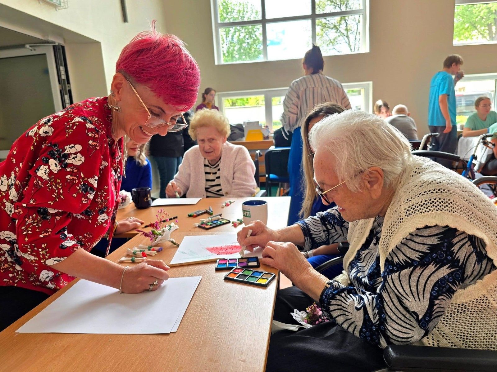 Seniorzy wykonujący prace plastyczne.