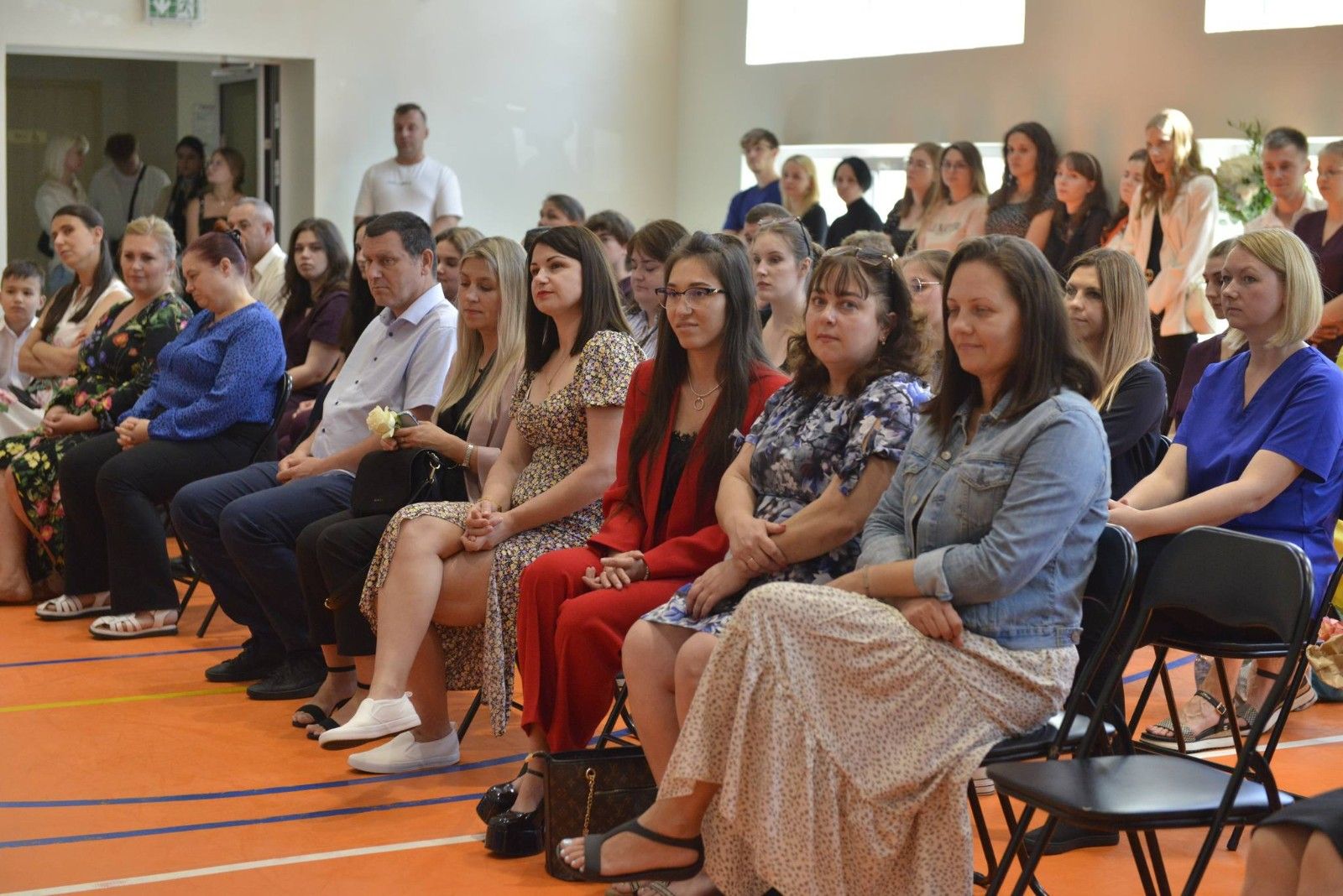 Uczniowie siedzący na hali sportowej