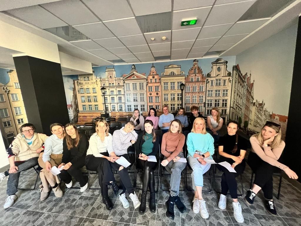 Grupowe zdjęcie uczniów na tle zdjęcia budynków.