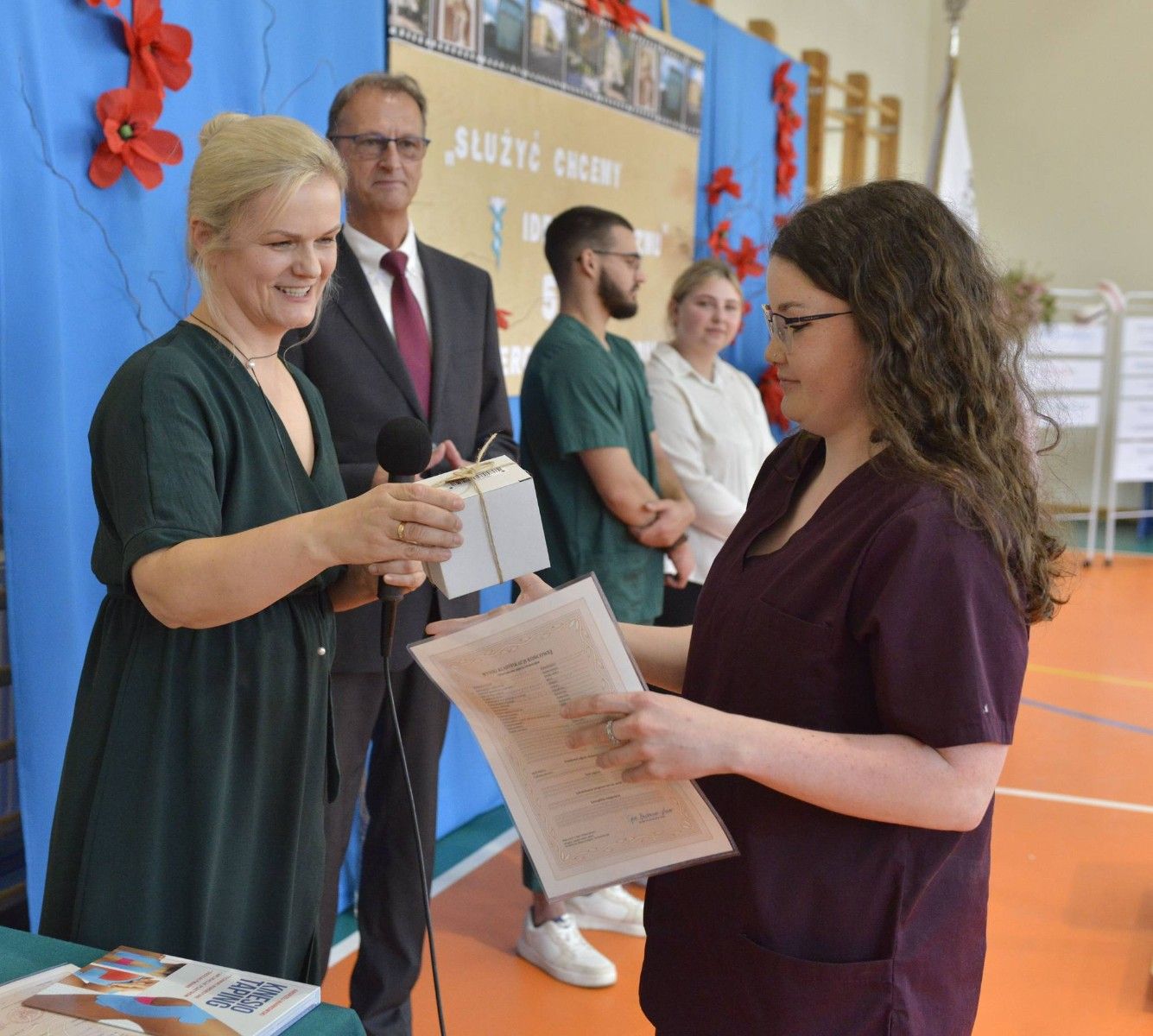 Uczennica odbierająca świadectwo od nauczyciela.