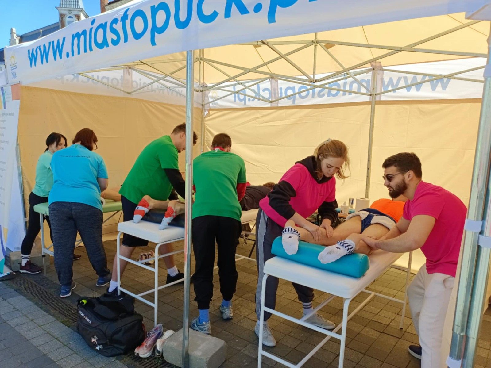 Uczniowie wykonujący w namiocie masarz nóg uczestnikom biegu.