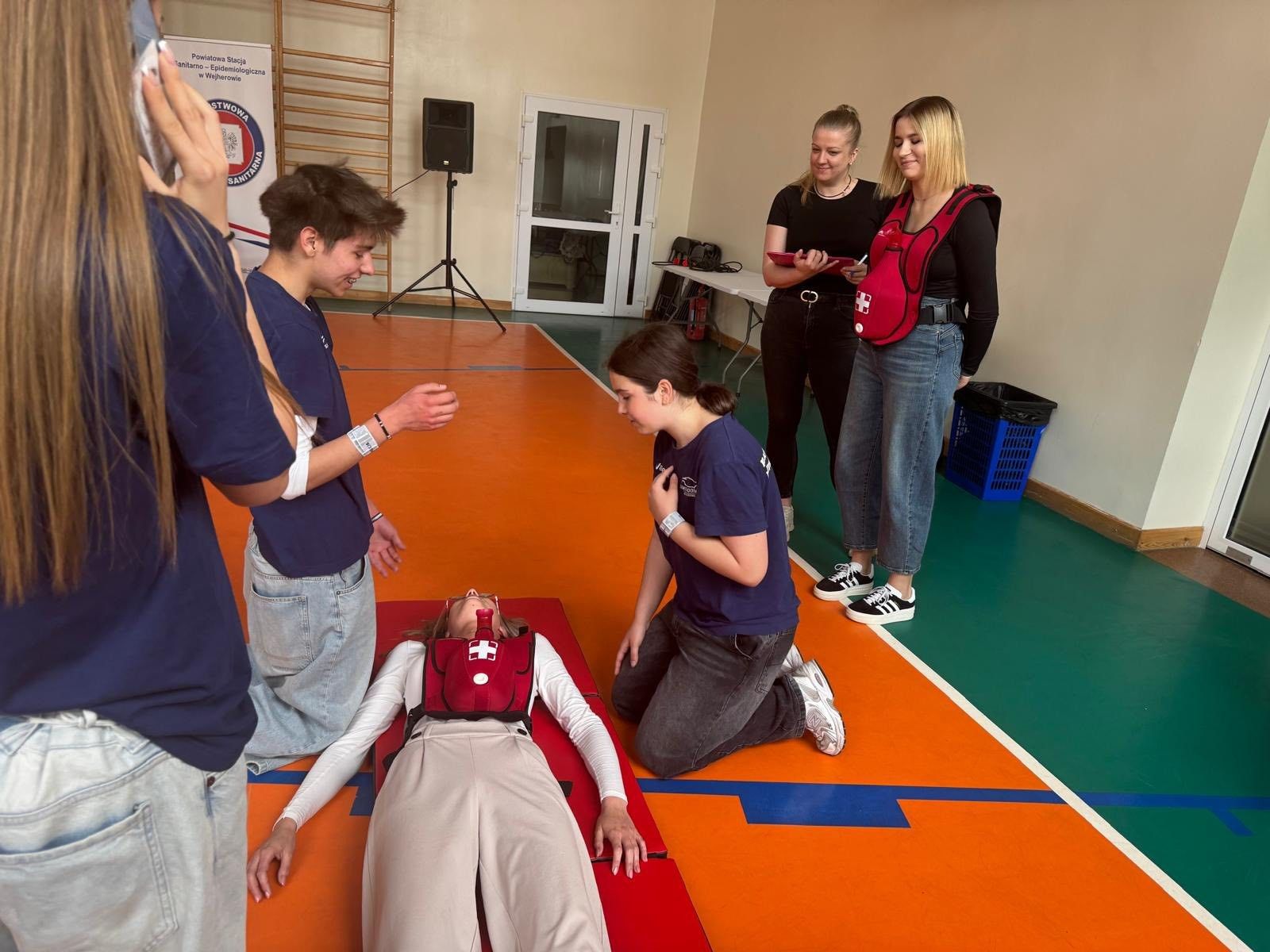 Uczestnicy gry ratujący leżącą osobę.