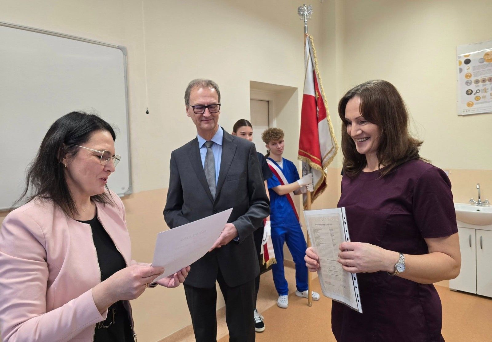 Zdjęcie z dyrektorem i nauczycielem wręczającym dyplom wraz z upominkiem.