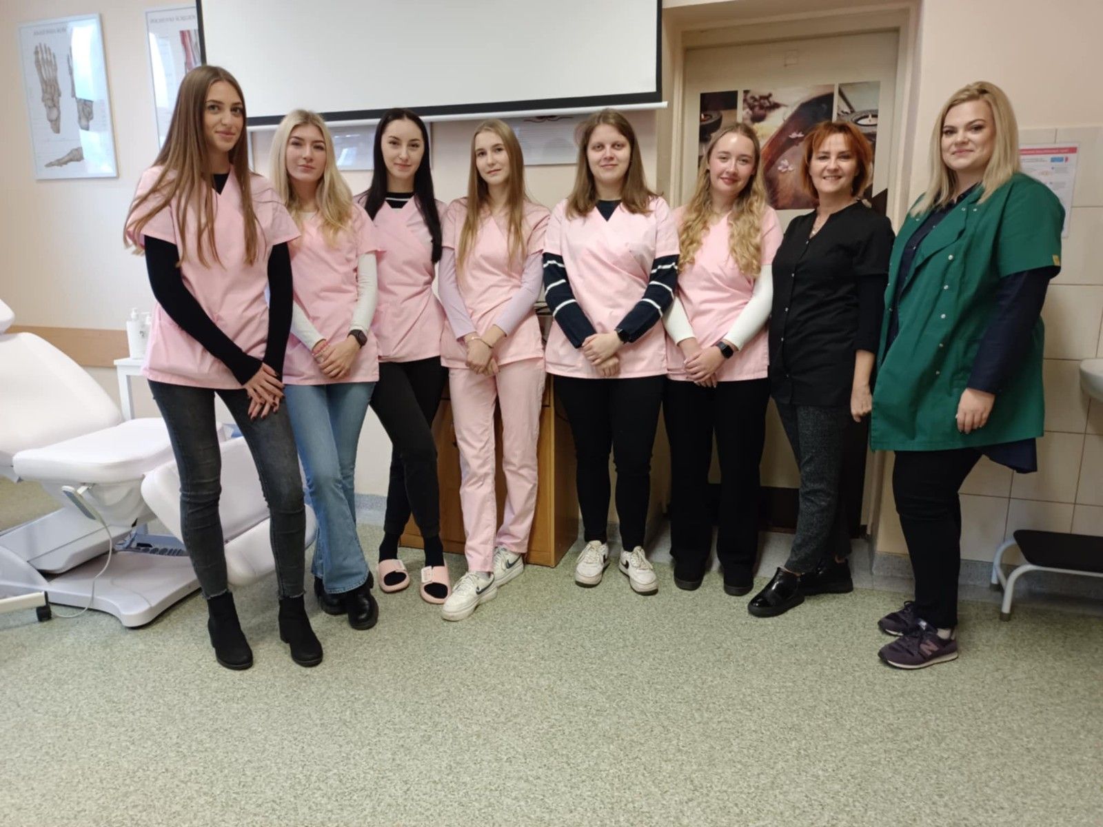 Wspólne zdjęcie uczennic  w różowych fartuchach wraz z nauczycielami.