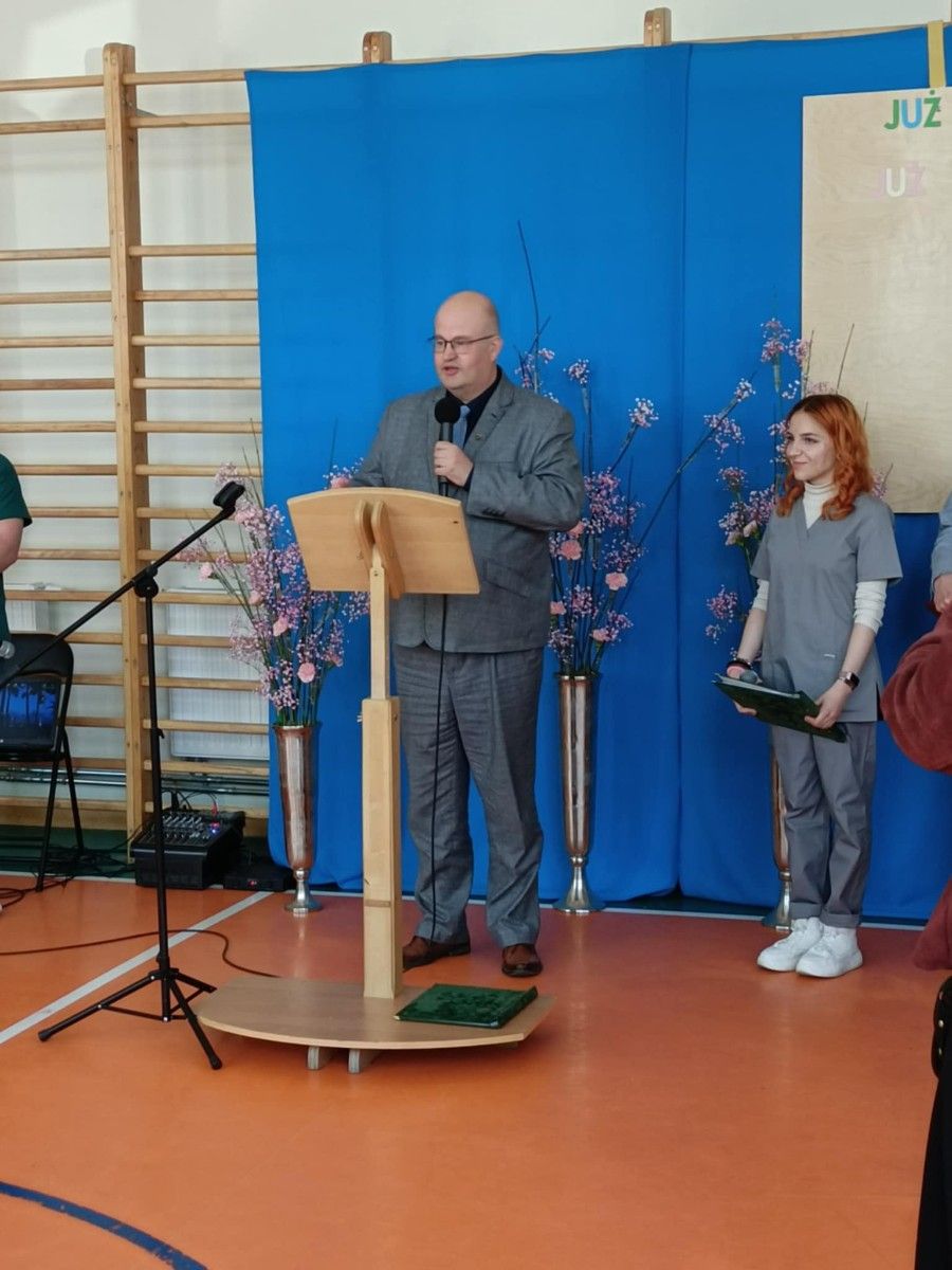 Przemawiający Starosta Wejherowski przez mikrofon na hali sportowej.