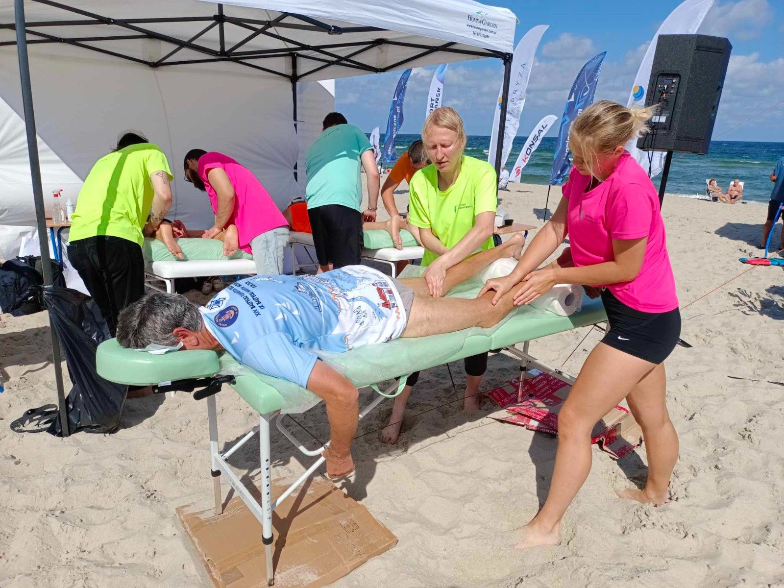 Uczennice masujące sportowca na stole do masażu. 