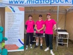 Triathlon STONEMAN uczniowie w różowych koszulkach przy banerze szkoły.