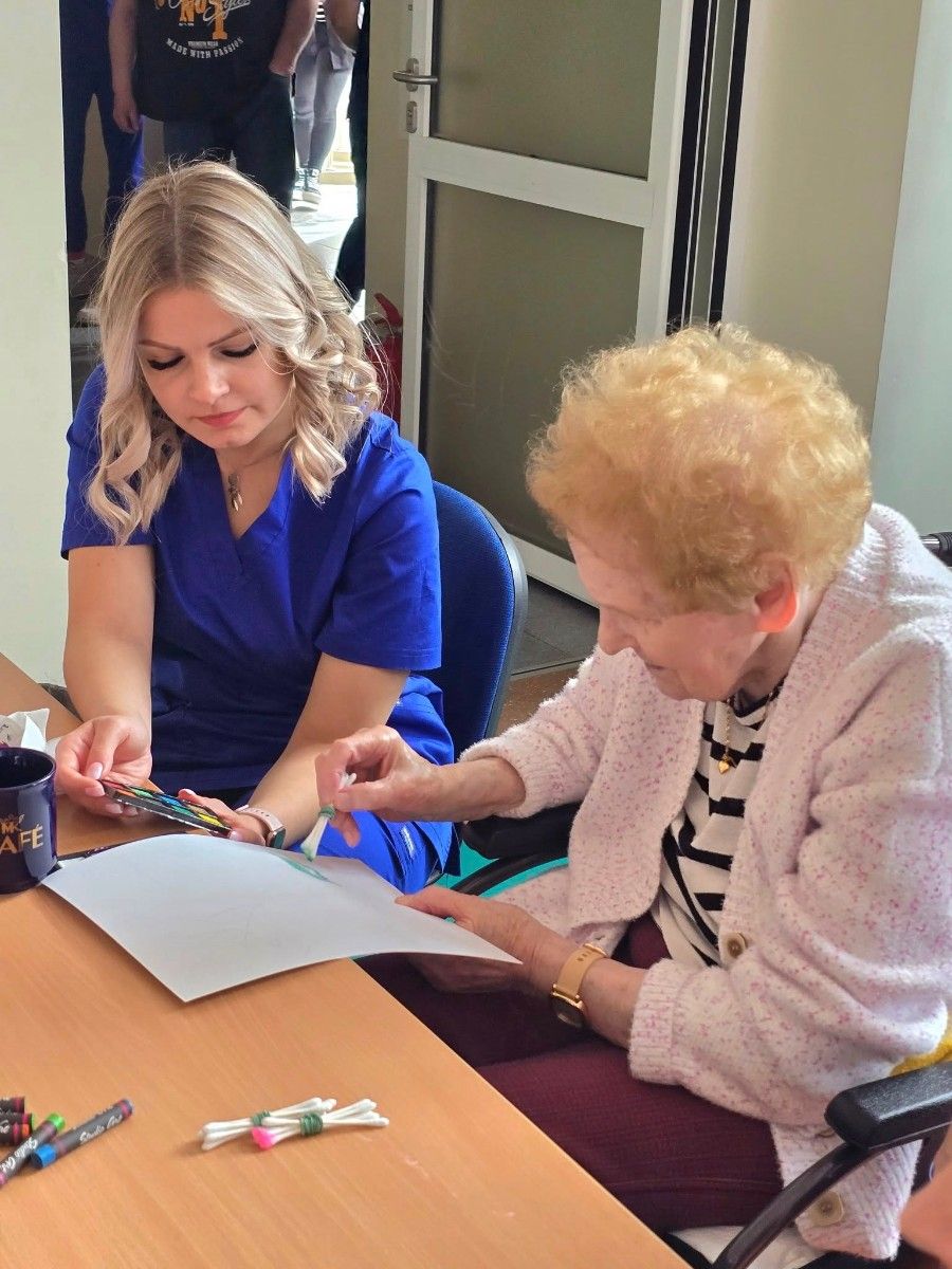 Uczennica wspomagająca seniorkę przy pracach plastycznych.