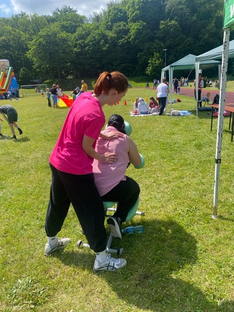 Uczennica wykonująca masarz ramion na specjalnym krześle.