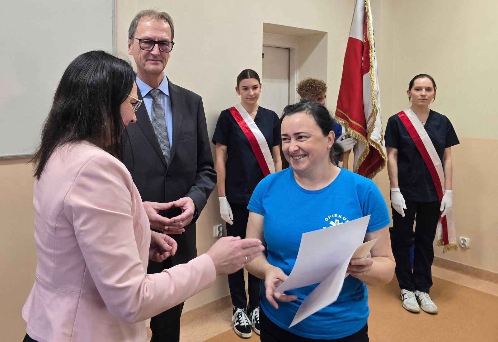 Zdjęcie z dyrektorem i nauczycielem wręczającym dyplom wraz z upominkiem.