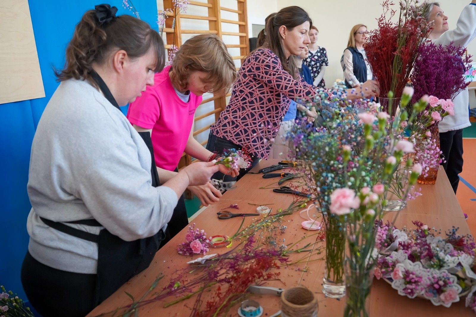 Seniorzy wykonujący prace florystyczne z kwiatami.