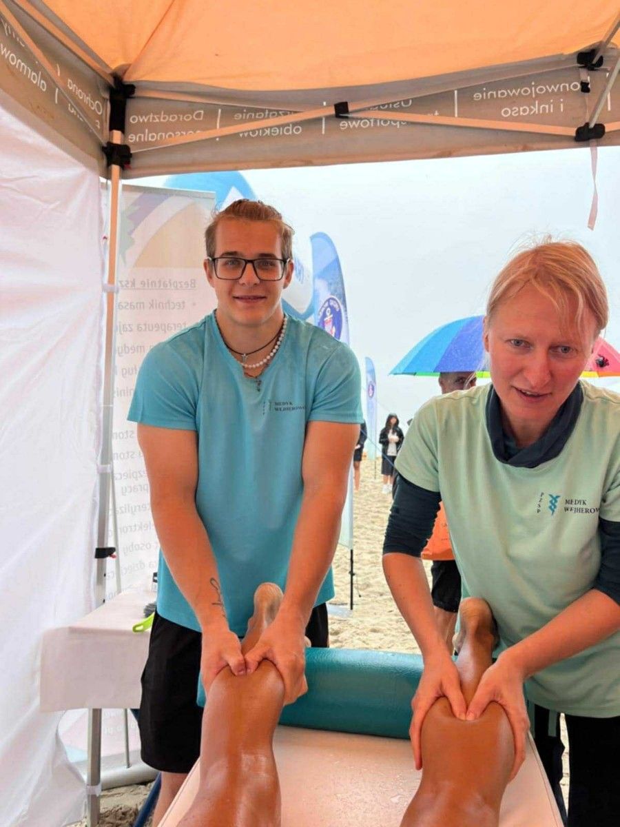 Masaż nóg na stole do masażu przez uczniów uczestnika maratonu.