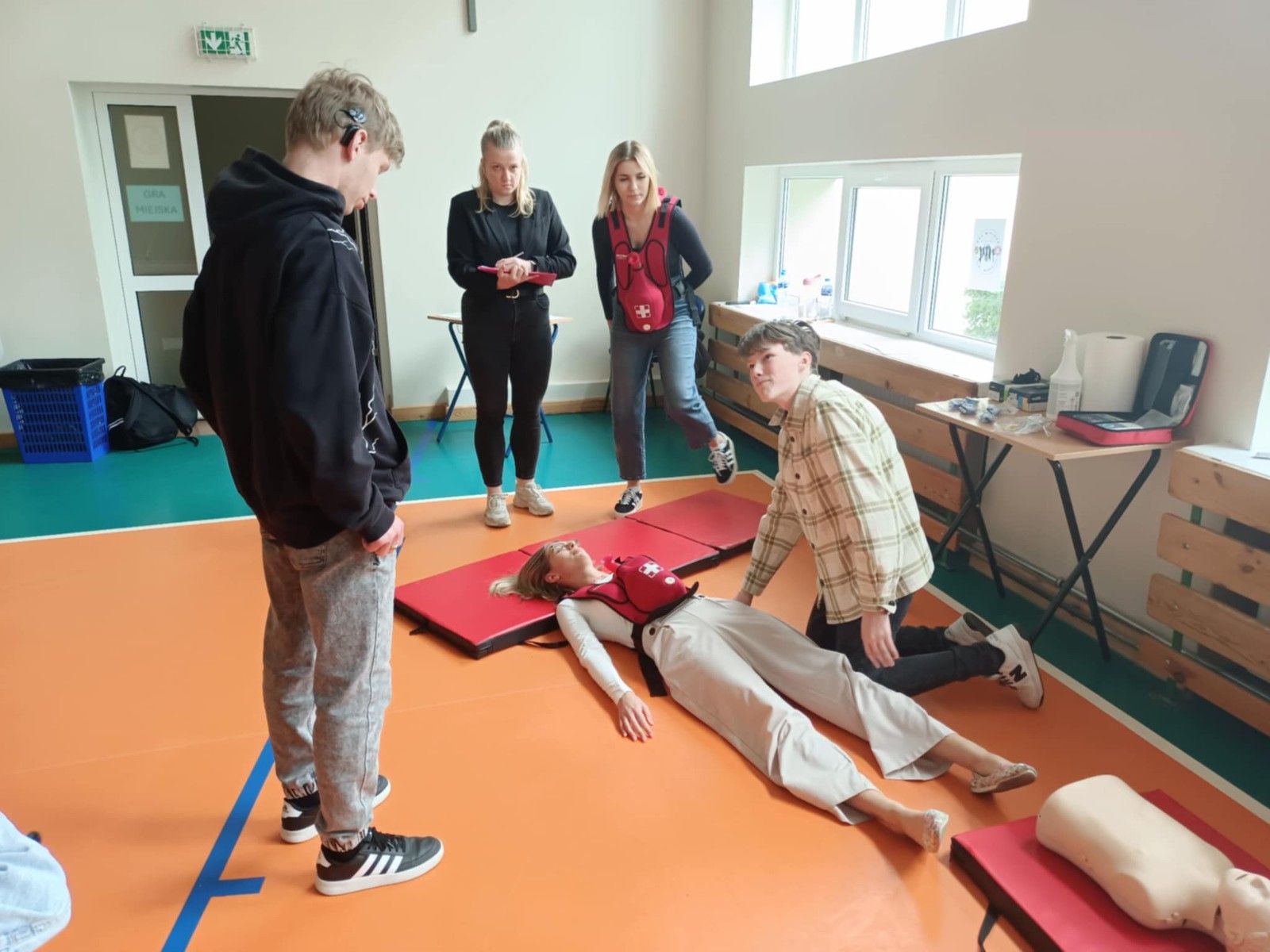 Ratownicy prezentujący ratowanie leżącego.