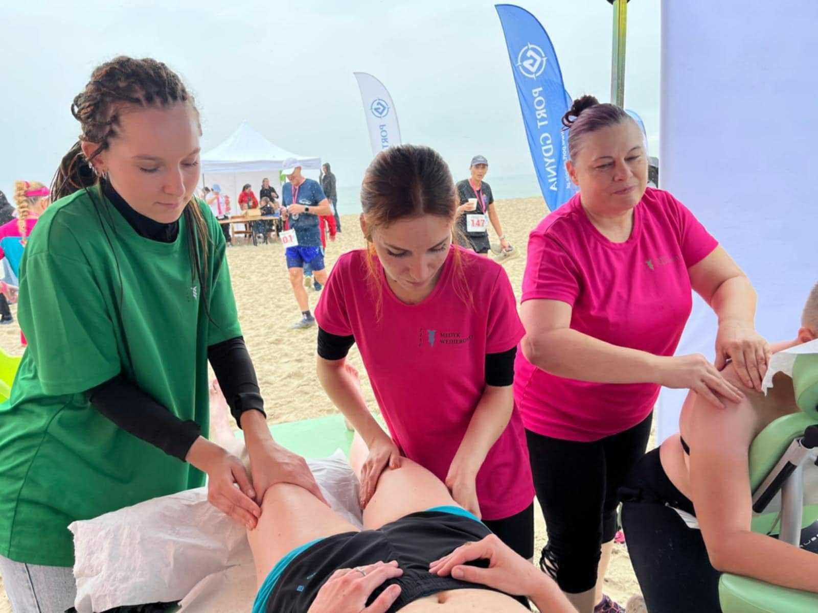 Masaż nóg na stole do masażu przez uczniów uczestnika maratonu.