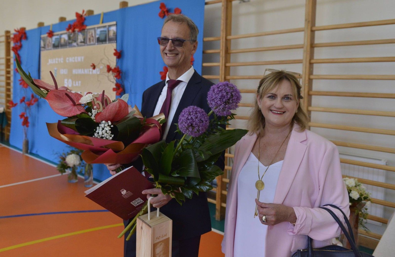 Dyrektor Szkoły odbierający kwiaty od Pani Dyrektor Biblioteki