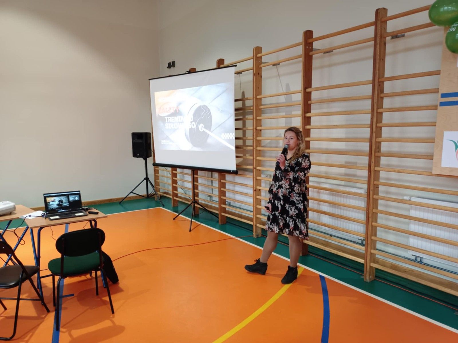 Pani wyświetlająca prezentację na hali sportwej.