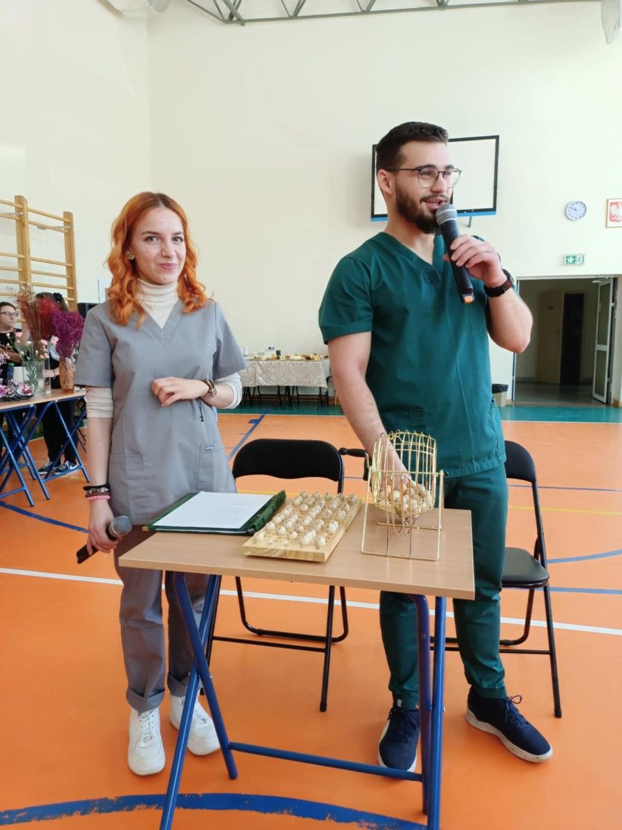 Uczniowie prowadzący grę w bingo na hali sportowej.