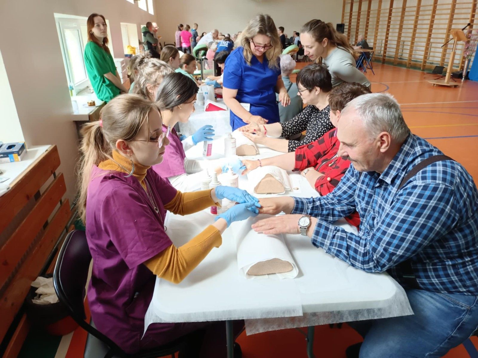 Uczennice wykonujące zabiegi pielęgnacyjne dłoni seniorów.
