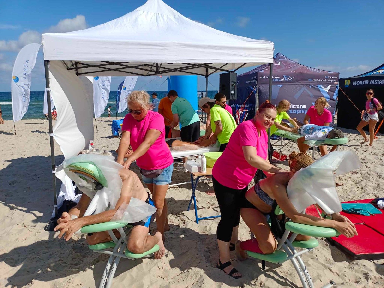 Uczennice masujące sportowców na plaży na krzesłach do masażu. 