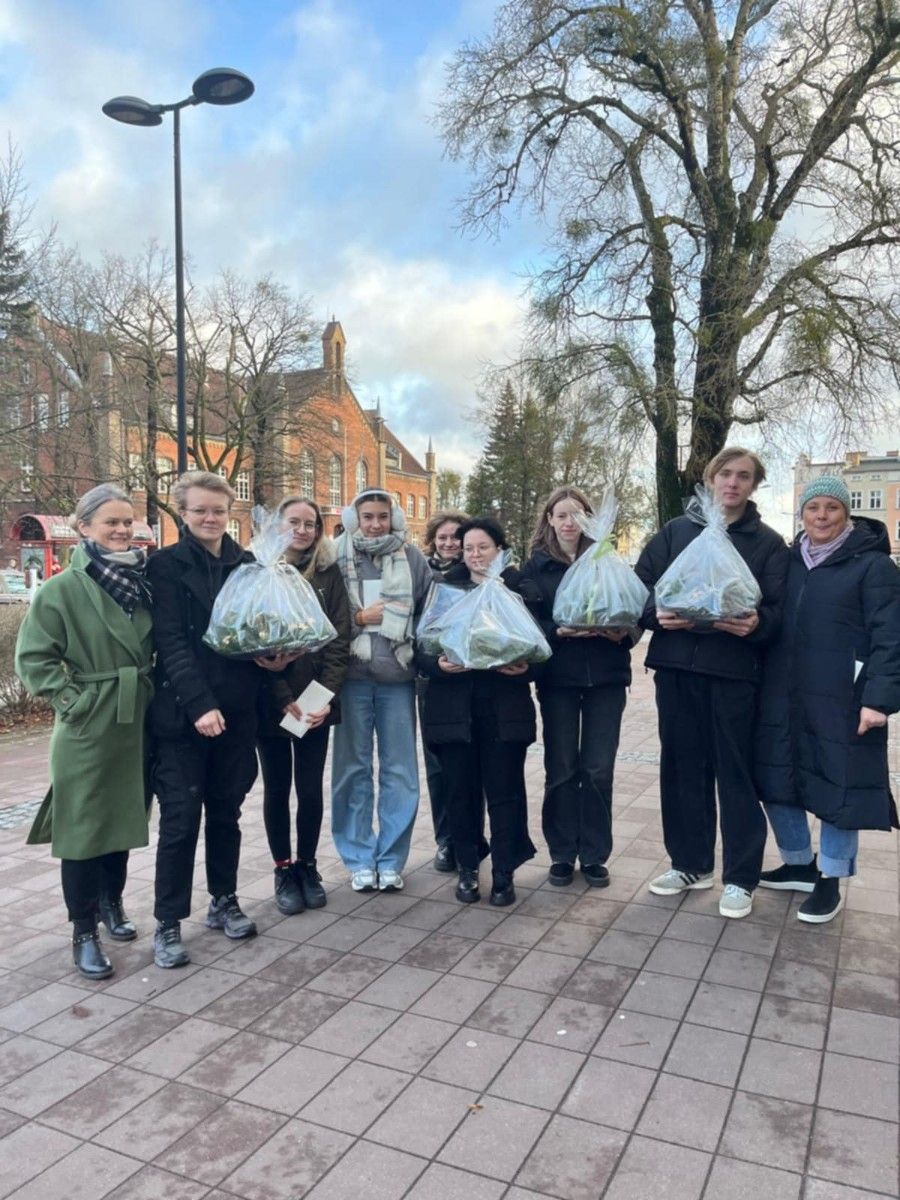 Uczniowie stojący na tle Szkoły Podstawowej nr 9 w Wejherowie z prezentami.