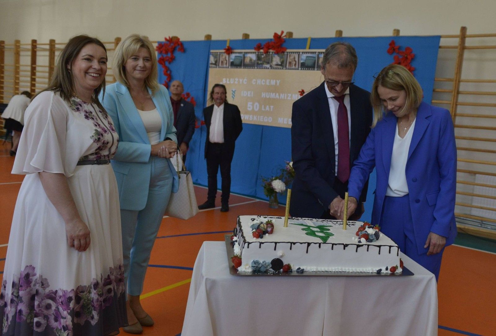 Dyrekcja szkoły wykonująca pierwsze cięcie uroczystego tortu.