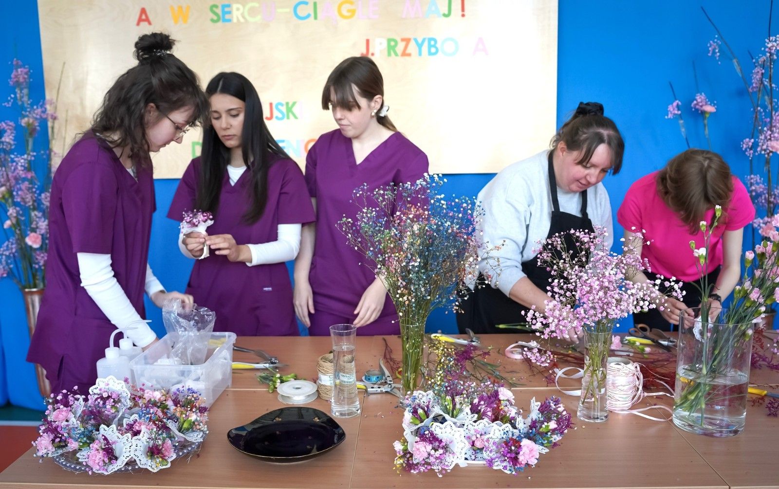 Uczniowie i seniorzy wykonujący wspólne prace florystyczne.