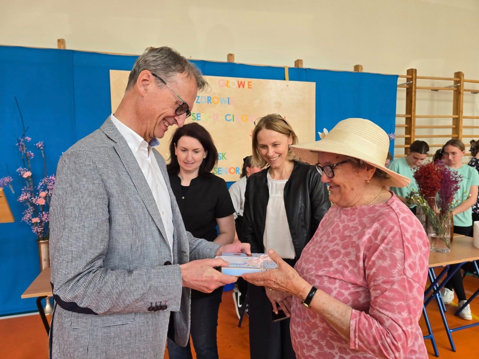 Dyrektor wręczający upominek seniorce.