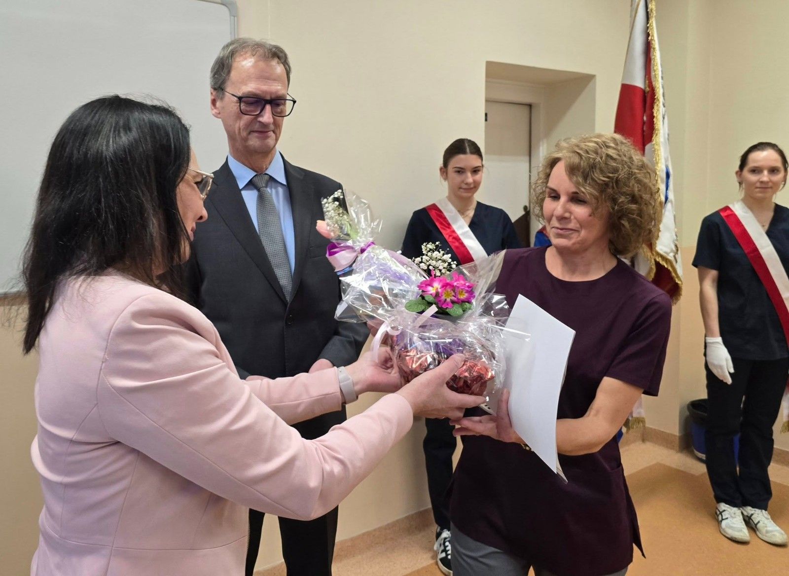 Zdjęcie z dyrektorem i nauczycielem wręczającym dyplom wraz z upominkiem.