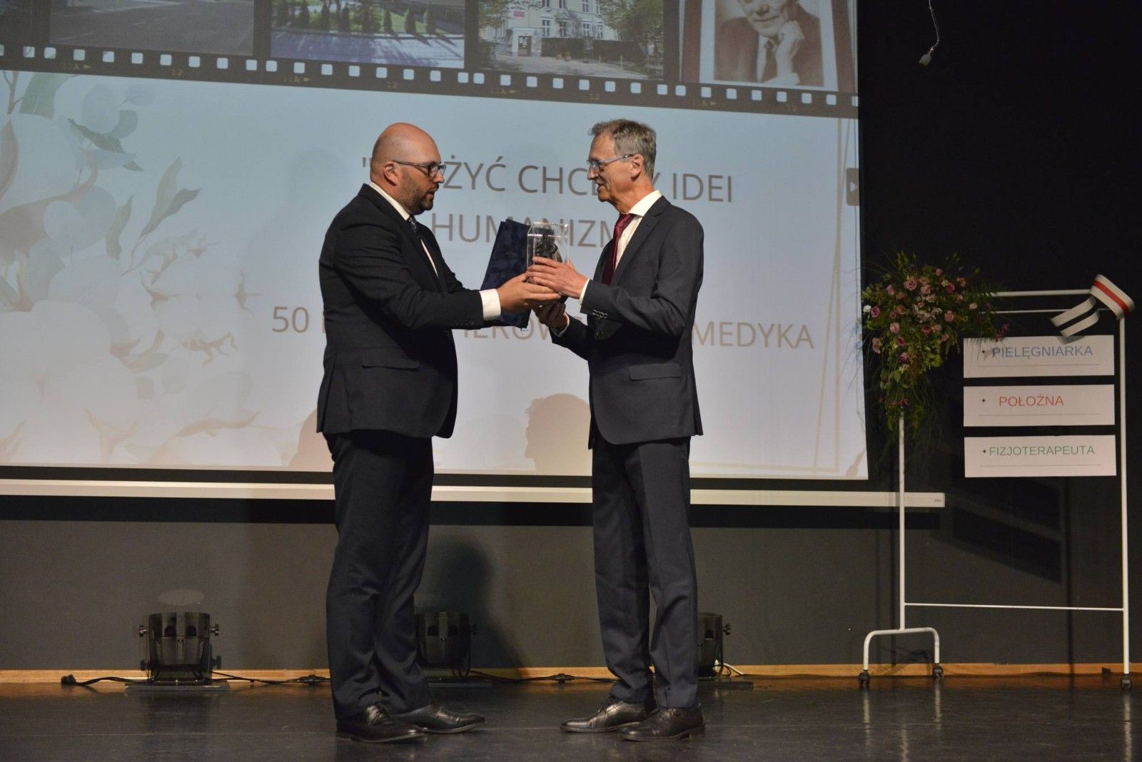 Dyrektor odbierający podziękowania i nagrodę na scenie.