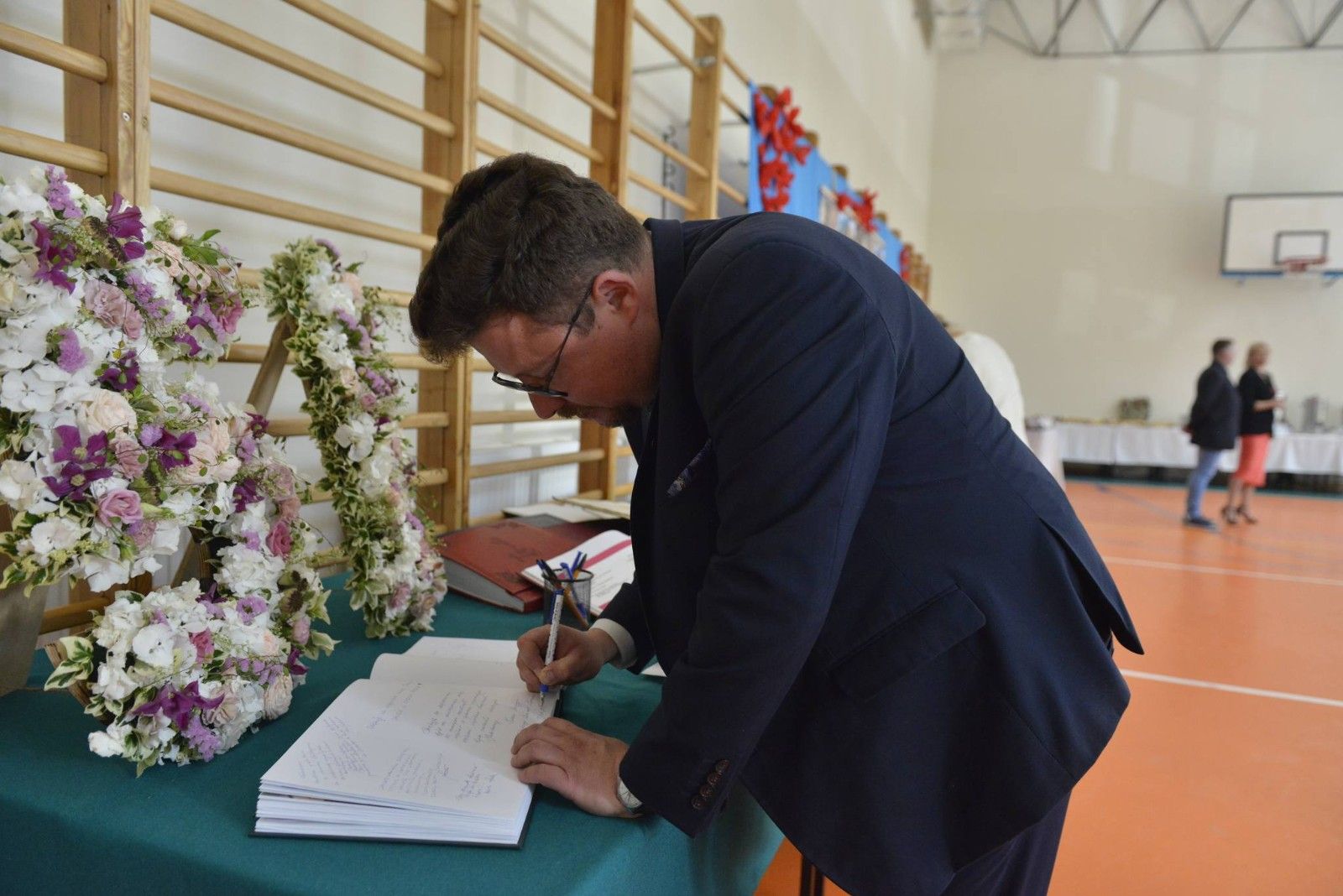 Gości wpisujący się do księgi pamiątkowej w szkole.